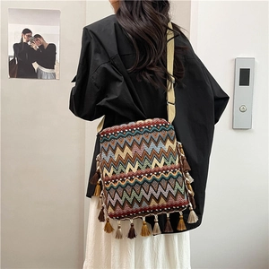 Détail macro du sac bohème tissé avec motifs géométriques colorés et décorations à franges