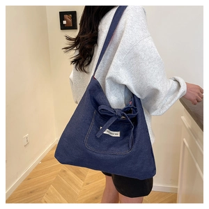 Close-up of a blue denim tote bag with a decorative bow and woven label detail