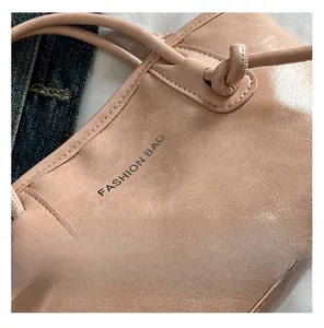 Détail du sac cabas rose montrant la bandoulière nouée et l'imprimé du logo