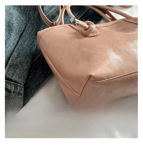 Gros plan sur la texture en similicuir rose et les détails métalliques du grand cabas