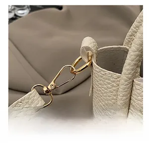 Close-up of litchi texture leather and golden metal hooks on a beige bucket bag