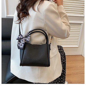 Detail of black lychee grain leather handbag with silk scarf on handle and Fashion logo