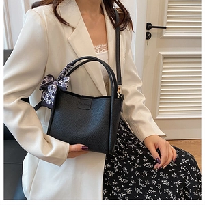 Detail of black litchi texture PU leather bucket bag with fashion stamp and silk scarf bow