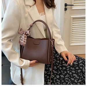 Detail of dark brown leather bucket bag with plaid silk scarf and adjustable strap