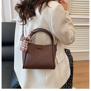 Deep brown lychee pattern leather bucket bag with silk scarf on model's shoulder