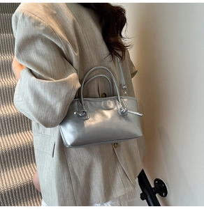 Gros plan du sac cabas argenté avec nœuds décoratifs porté par un mannequin à l'épaule