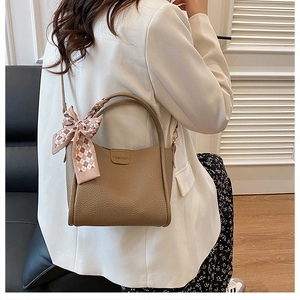 Detailed texture of caramel litchi grain leather tote with a pink plaid silk scarf bow