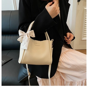 Detail of beige lychee pattern handbag with fashion label and decorative silk scarf