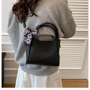 Detailed shot of black lychee grain bucket bag with checkered scarf and Fashion stamp