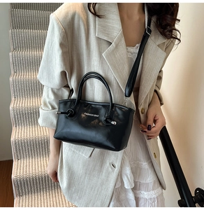 Détail d'un sac cabas en cuir PU noir avec poignées incurvées et inscription blanche chic