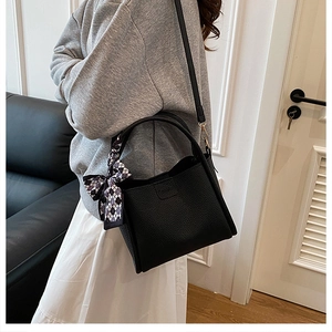 Chic black litchi grain bucket bag with checkered silk scarf accessory worn by model