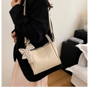 Close-up of beige lychee textured shoulder bag with fashion embossing and pink silk scarf detail