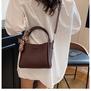 Detail of dark brown pebble leather bucket bag with a decorative checkered silk scarf knot