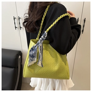 Detail of green woven tote bag with handle and chic blue and white silk scarf decoration