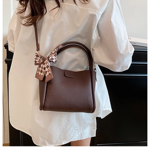 Brown lychee leather bucket bag with checkered scarf accent shown from a back view