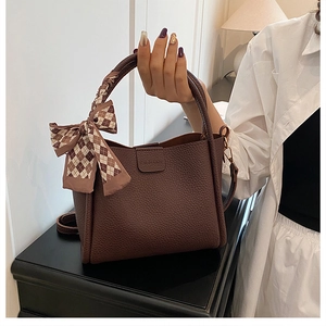 Detail of dark brown pebble leather bag with silk scarf handle and embossed logo