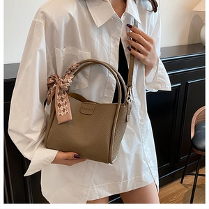 Brown lychee leather bucket bag with pink checkered scarf detail on handle