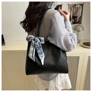 Detail of black woven tote bag featuring a decorative blue silk scarf on the handle