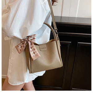 Detail of dark khaki leather bag with lychee texture and stylish plaid silk scarf accent