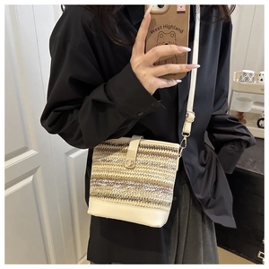 Detailed close-up of woven straw texture and cream leather trim on stylish bucket bag