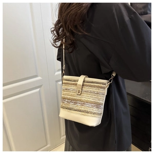 Close-up of contrast woven bucket bag featuring cream leather trim and gold metal clasp