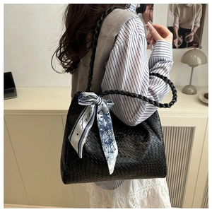 Close-up of black woven tote bag featuring a decorative silk scarf and textured strap