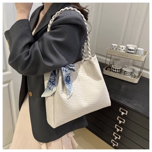 Detail of white woven tote bag featuring a decorative blue silk scarf on handle
