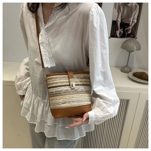 Detailed view of straw bucket bag with leather trim and gold twist lock on model