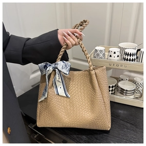 Detail of khaki tote bag with textured surface and silk scarf wrapped around handle