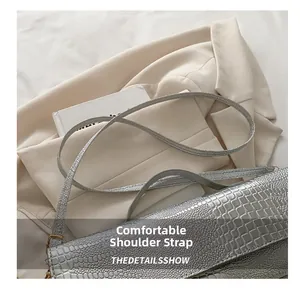 Detailed view of silver crocodile pattern shoulder strap with golden metal hardware buckle
