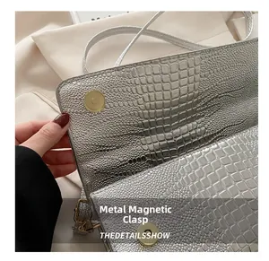 Detail of silver crocodile texture leather bag featuring golden magnetic snap closure