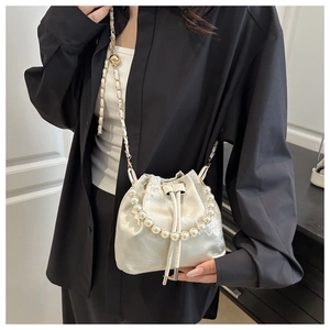 Close-up of beige satin bucket bag with floral embroidery and elegant pearl handle