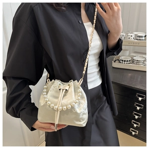 Detail of champagne silk bucket bag with white floral embroidery and pearl handle