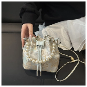 Close-up of drawstring bucket bag featuring floral brocade and pearl handle detail
