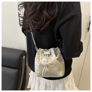 Detail of light blue embroidered bucket bag with pearl handle worn by a model