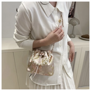 Detail of light pink satin bucket bag with floral embroidery and pearl handle