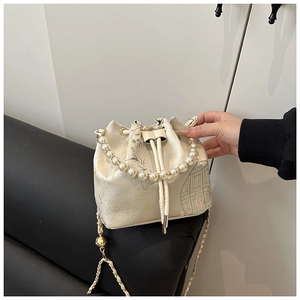 Detailed view of cream silk bucket bag with flower embroidery and pearl handle