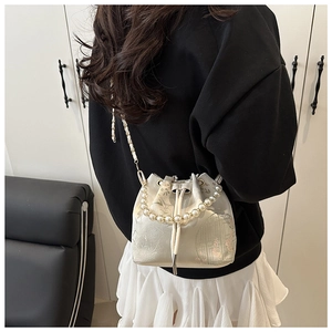 Detail showing embroidered satin bucket bag with pearl handle and floral pattern