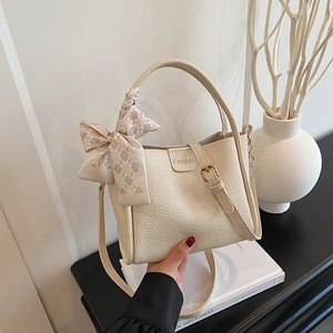 Elegant cream bucket bag with lychee texture, silk scarf handle, and crossbody strap