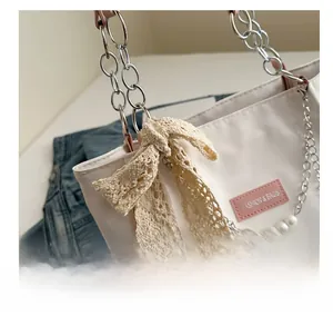Detail of white PU tote with silver chain handle and lace bow decorative accents