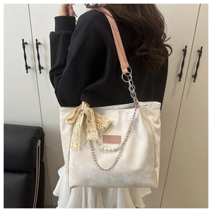 Detail of white tote bag with pink leather strap, silver chain, and lace bow decoration