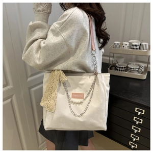 Detail view of white canvas tote bag with pearl chain accessories and pink shoulder strap