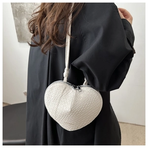 Detail showing creamy white heart-shaped crossbody bag with crocodile leather texture