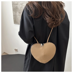 Detail of khaki heart-shaped bag with crocodile embossed texture and metal zippers