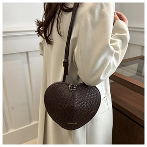 Detail shot of a dark brown heart bag showing woven texture and gold fashion logo