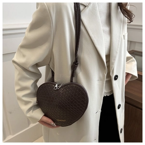 Detail of dark brown heart-shaped crossbody bag with crocodile embossed texture and zippers