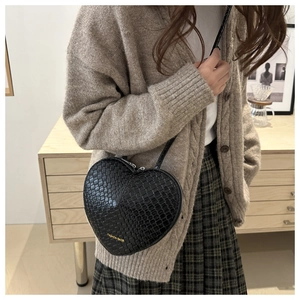 Vue détaillée du sac à bandoulière noir en forme de cœur avec texture tissée sur mannequin