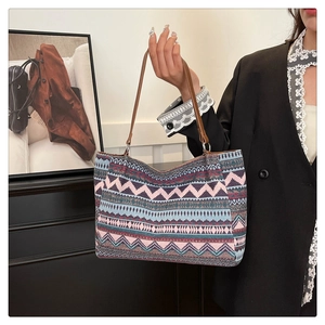 Detail of bohemian tote bag with geometric woven patterns and brown leather straps