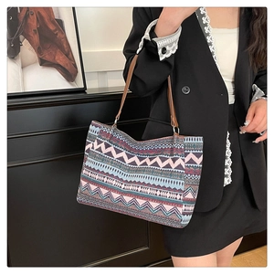 Ethnic knit tote bag with geometric patterns and leather straps shown on a female model