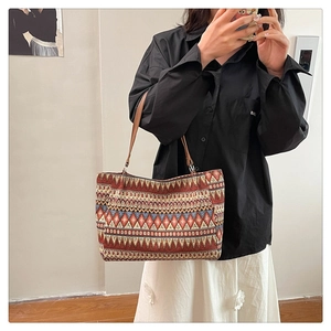 Ethnic knit tote bag with red and blue geometric patterns and brown leather handles